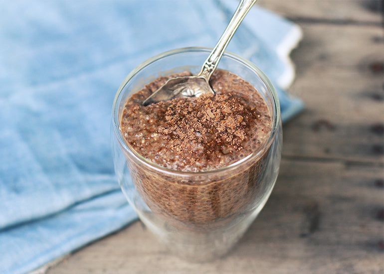 A glass filled with chocolate chia pudding made with Navitas Organics Chia Seeds, Cacao Powder, and Cacao & Greens Essential Blend.