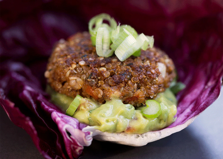 A vegan Tex-Mex style veggie burger made with Navitas Organics Chia Seeds and Hemp Seeds, sitting on a base of guacamole.