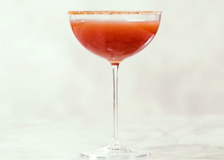 A tall martini glass filled with a pomegranate martini made with Navitas Organics Pomegranate Powder.
