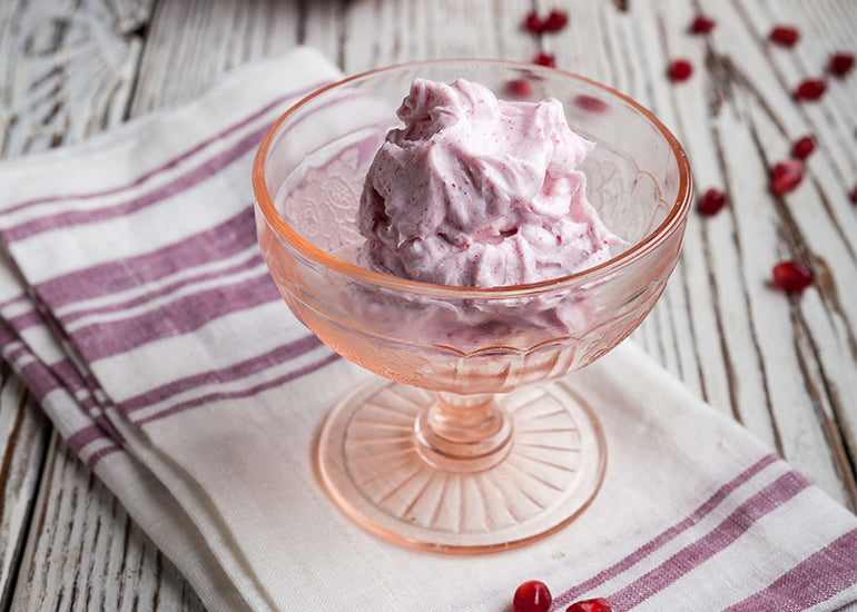 A glass dish filled with a pink moisturizing body butter made with Navitas Organics Pomegranate Powder.