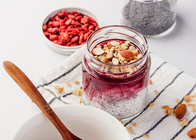 A mason jar filled with chia pudding made with Navitas Organics Chia Seeds, topped with a goji berry jam made with Navitas Organics Goji Berries and Goji Powder.