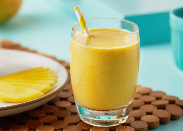 A glass filled with a tropical immunity boosting smoothie made with Navitas Organics Camu Powder.