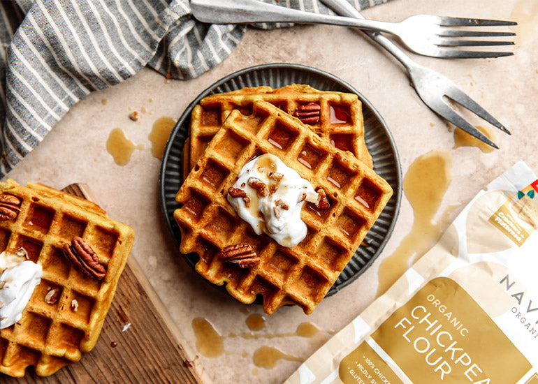A plate of pumpkin spice waffles made with Navitas Organics Chickpea Flour, topped with yogurt, pecans and pure maple syrup.