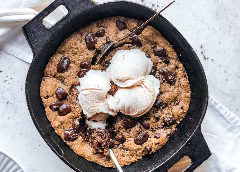 A chocolate chip cookie skillet made with Navitas Organics Cacao Butter Wafers, topped with ice cream.