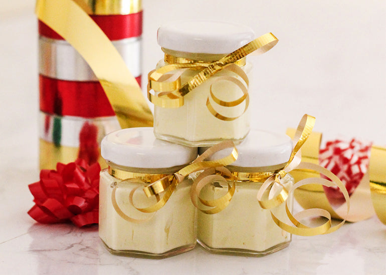 Small jars of whipped peppermint body butter made with Navitas Organics Cacao Butter wrapped with festive holiday ribbon.
