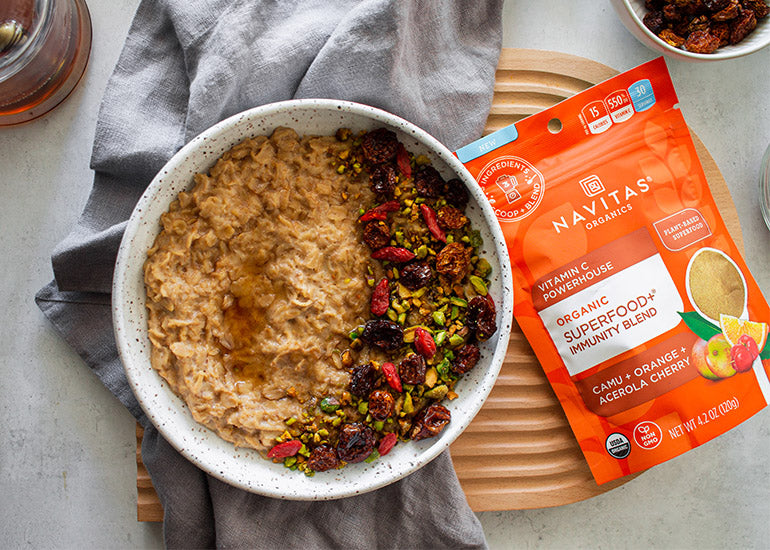 A bowl of oatmeal made with Navitas Organics Superfood+ Immunity Blend topped with crushed pistachios and Navitas Organics Goldenberries and Goji Berries.