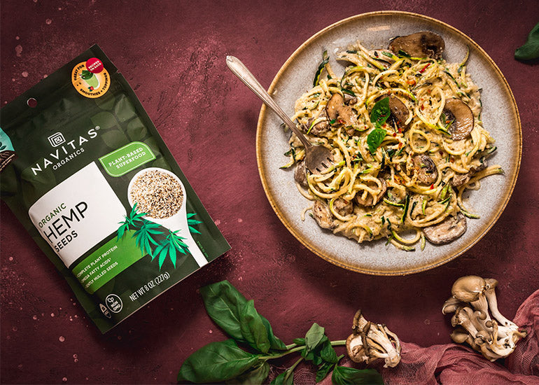 A plate of zucchini noodles topped with hemp alfredo made with Navitas Organics Hemp Seeds.