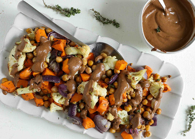 A dish of roasted vegetables topped with a mole sauce made with Navitas Organics Cacao Powder