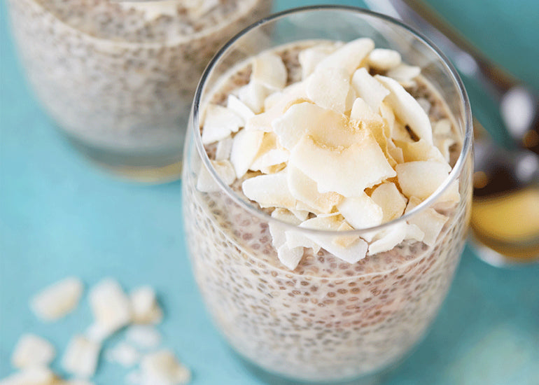 Two glasses filled with chia pudding made with Navitas Organics Chia Seeds, topped with toasted coconut flakes.