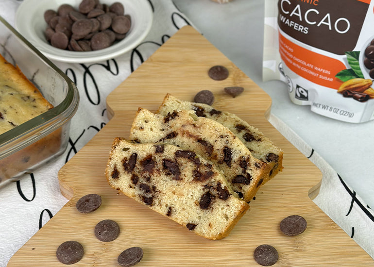 Slices of a chocolate chip loaf cake made with Navitas Organics Semi-sweet Cacao Wafers laying on a cutting board