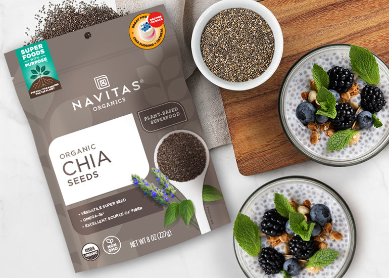 Navitas Organics Chia Seeds with two jars filled with chia pudding topped with fresh berries and nuts