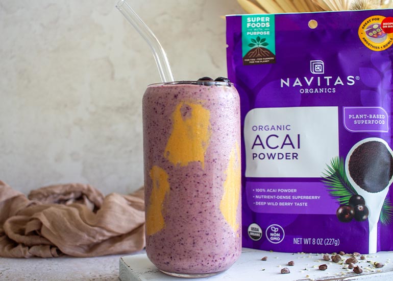 A tall glass filled with an acai peanut butter smoothie made with Navitas Organics Acai Powder, topped with Navitas Organics Hemp Seeds and Cacao Nibs