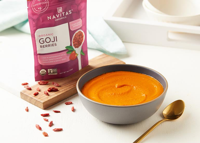 A bowl of creamy tomato miso soup with a bag of Navitas Organics Goji Berries