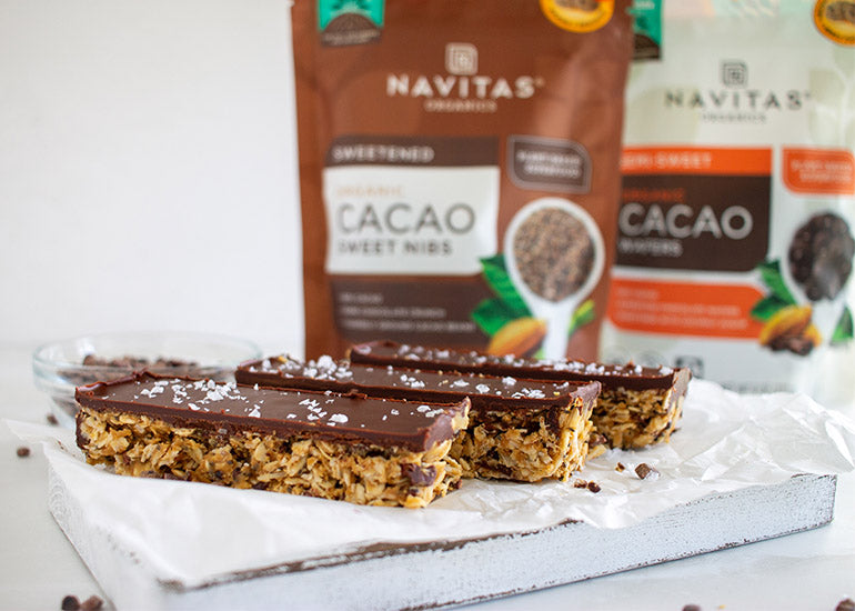A row of homemade no-bake chocolate-coated granola bars made with Navitas Organics Semi-sweet Cacao Wafers and Cacao Sweet Nibs
