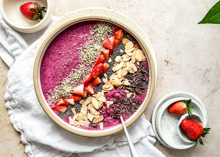 An acai bowl made with Navitas Organics Acai Powder topped with Navitas Organics Cacao Nibs, Chia Seeds and Hemp Seeds