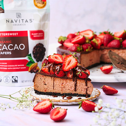 A strawberry chocolate cheesecake with a plated slice made with Navitas Organics Bittersweet Cacao Wafers