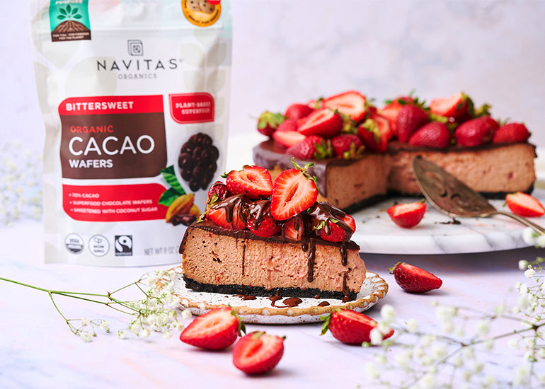 A strawberry chocolate cheesecake with a plated slice made with Navitas Organics Bittersweet Cacao Wafers