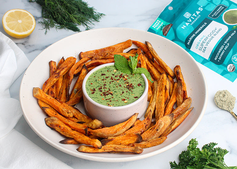 A plate filled with baked sweet potato fries surrounding a dish filled with a green goddess dipping sauce made with Navitas Organics Superfood+ Sea Veggie Blend