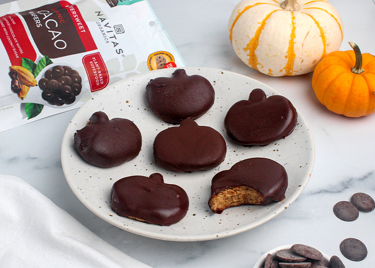 A plate topped with homemade chocolate peanut butter pumpkins made with Navitas Organics Bittersweet Cacao Wafers