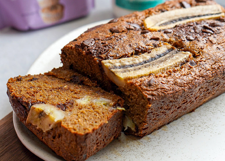 A sliced loaf of coconut chocolate chip banana bread made with Navitas Organics Semi-sweet Cacao Wafers, a healthy banana bread mix and organic coconut oil