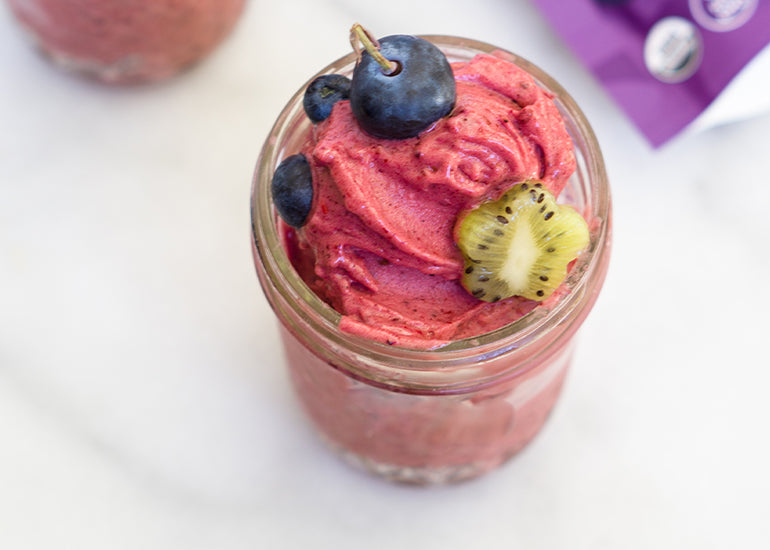 A mason jar filled with maqui berry nice cream made with Navitas Organics Elderberry Powder, topped with fresh kiwi fruit and blueberries