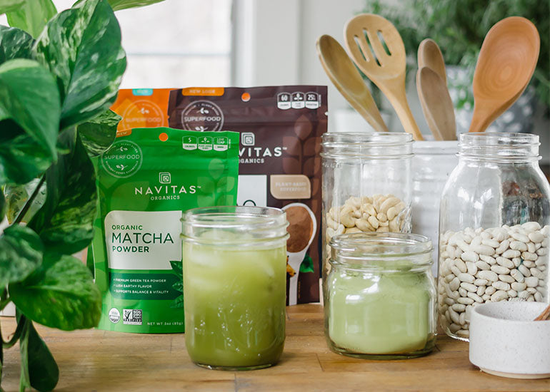 A variety of Navitas Organics superfoods and other sustainable ingredients in jars on a kitchen countertop