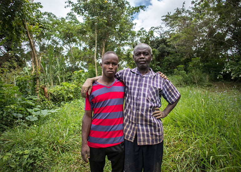 Two smallholder farmers standing together in a rainforest.
