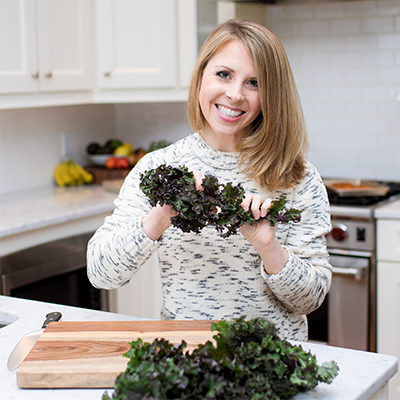 Erin Parekh, Integrative Nutritionist and Women's Wellness Expert, holding curly kale in her kitchen