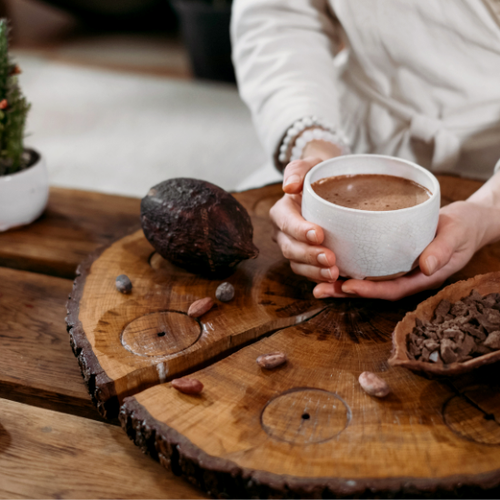 A woman holding a mug filled with hot chocolate made with Navitas Organics Fairtrade Certified Cacao.