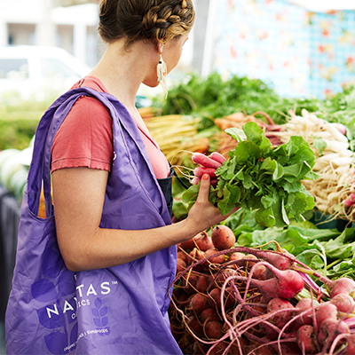 A woman picking out fresh produce at a farmer's market.