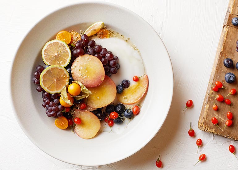 A fruit salad mixed with Navitas Organics superfoods in a bowl.