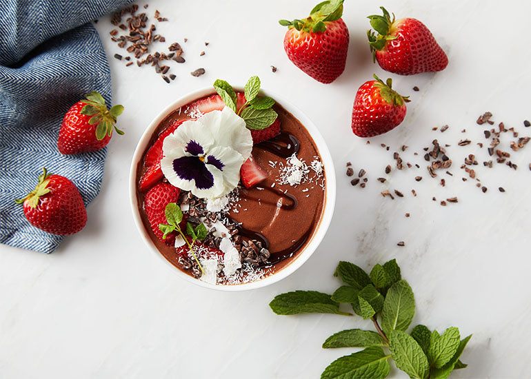 Smoothie bowl made with Navitas Organics Cacao Powder, topped with Navitas Organics Cacao Nibs, fresh strawberries and shaved coconut
