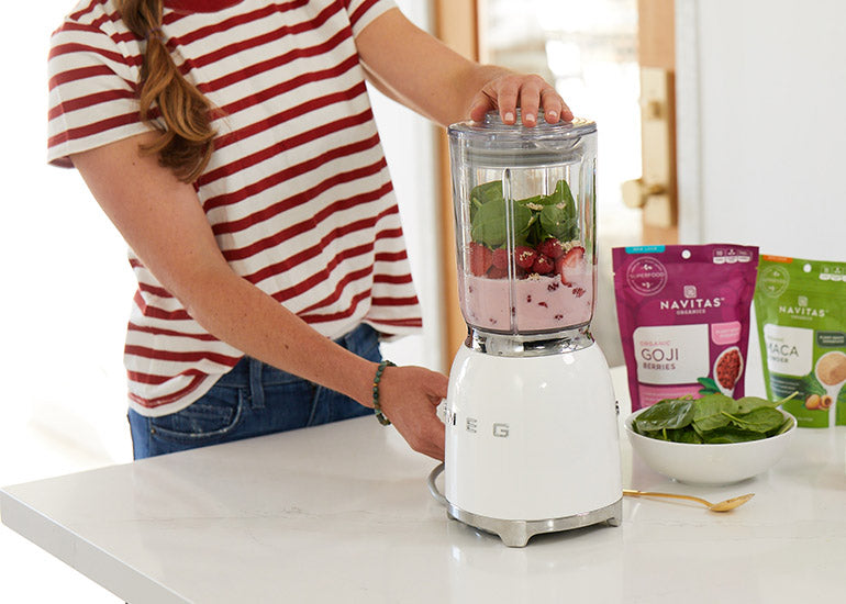 A woman blending a smoothie made with fresh fruit, greens and Navitas Organics superfoods.