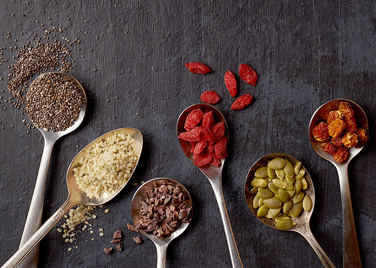 Spoons holding a variety of superfood seeds and berries