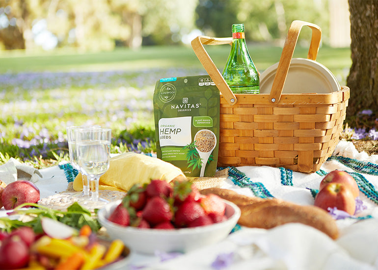 A picnic setup with fresh fruit, bread and Navitas Organics Hemp Seeds.