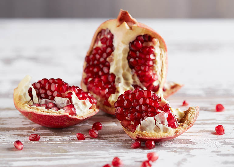 A fresh pomegranate fruit sliced open on a table