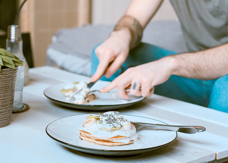 A man eating pancakes topped with yogurt and Navitas Organics Chia Seeds