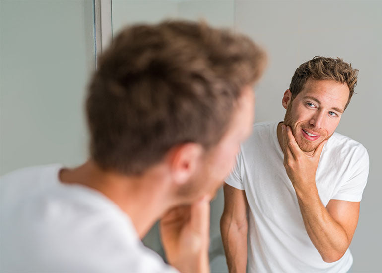 A middle-aged man looking at himself in the mirror
