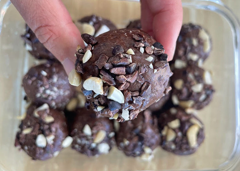 Chocolate protein balls made with Navitas Organics Cacao Powder, coated in chopped nuts and Navitas Organics Cacao Nibs. 