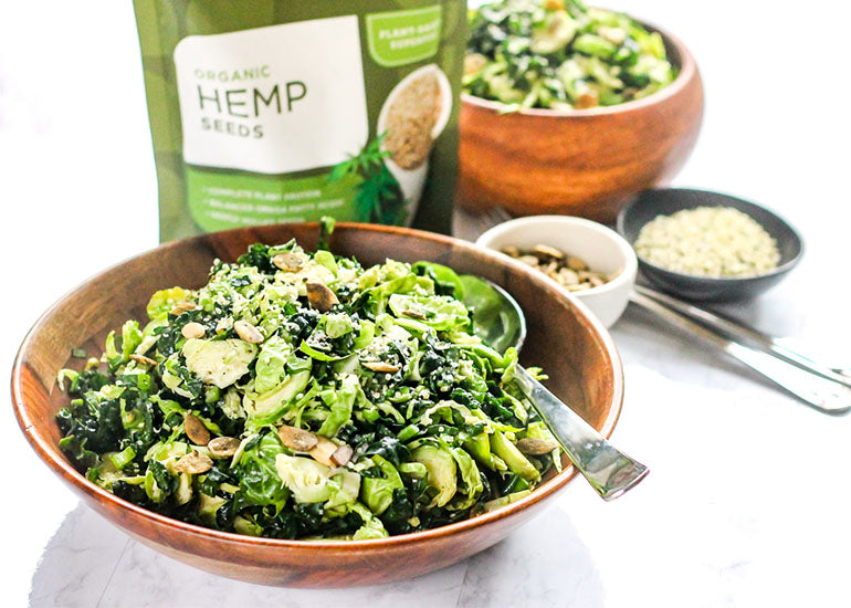 A kale and Brussels salad topped with Navitas Organics Hemp Seeds.