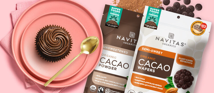 A plate with a chocolate cupcake and bags of Navitas Organics Cacao Powder and Semi-sweet Cacao Wafers.