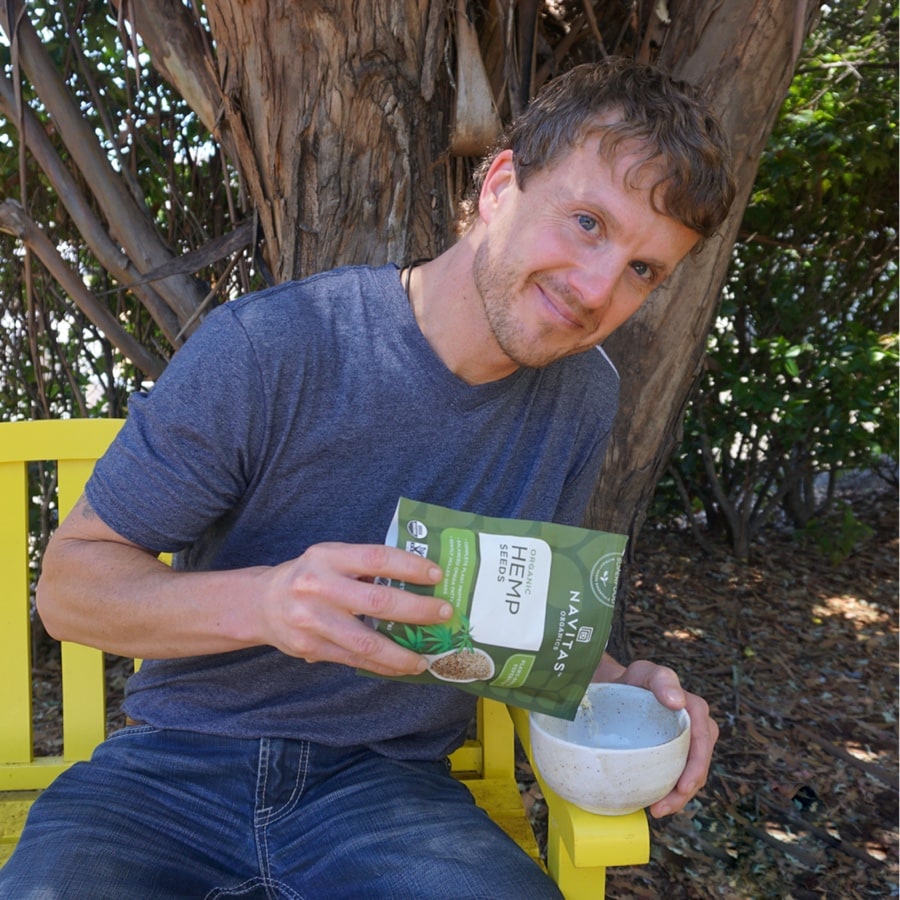 Arthur Mullins sitting on a bench outside with a bag of Navitas Organics Hemp seeds