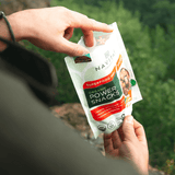 A young male hiker reaching into a bag of Navitas Organics Superfood PB&J Power Snacks.