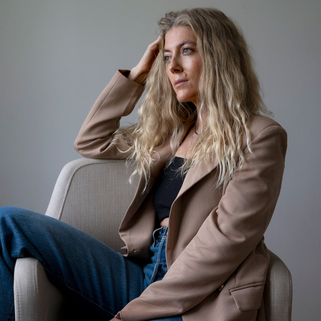 Freelance Writer Leslie K. Hughes sitting on a chair looking into the distance.