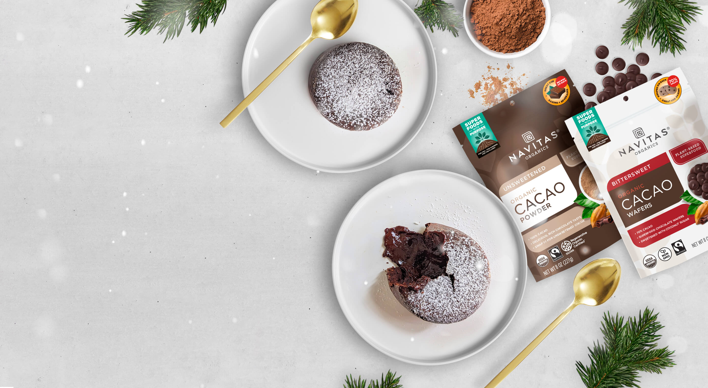 Navitas Organics Cacao Powder and Bittersweet Cacao Wafers with festive holiday decor and two plated mini chocolate mousse cakes