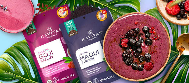 Bags of Navitas Organics Goji Berries and Maqui Powder spilling out product next to smoothies, palm leaves and a gold spoon against a colorful background.