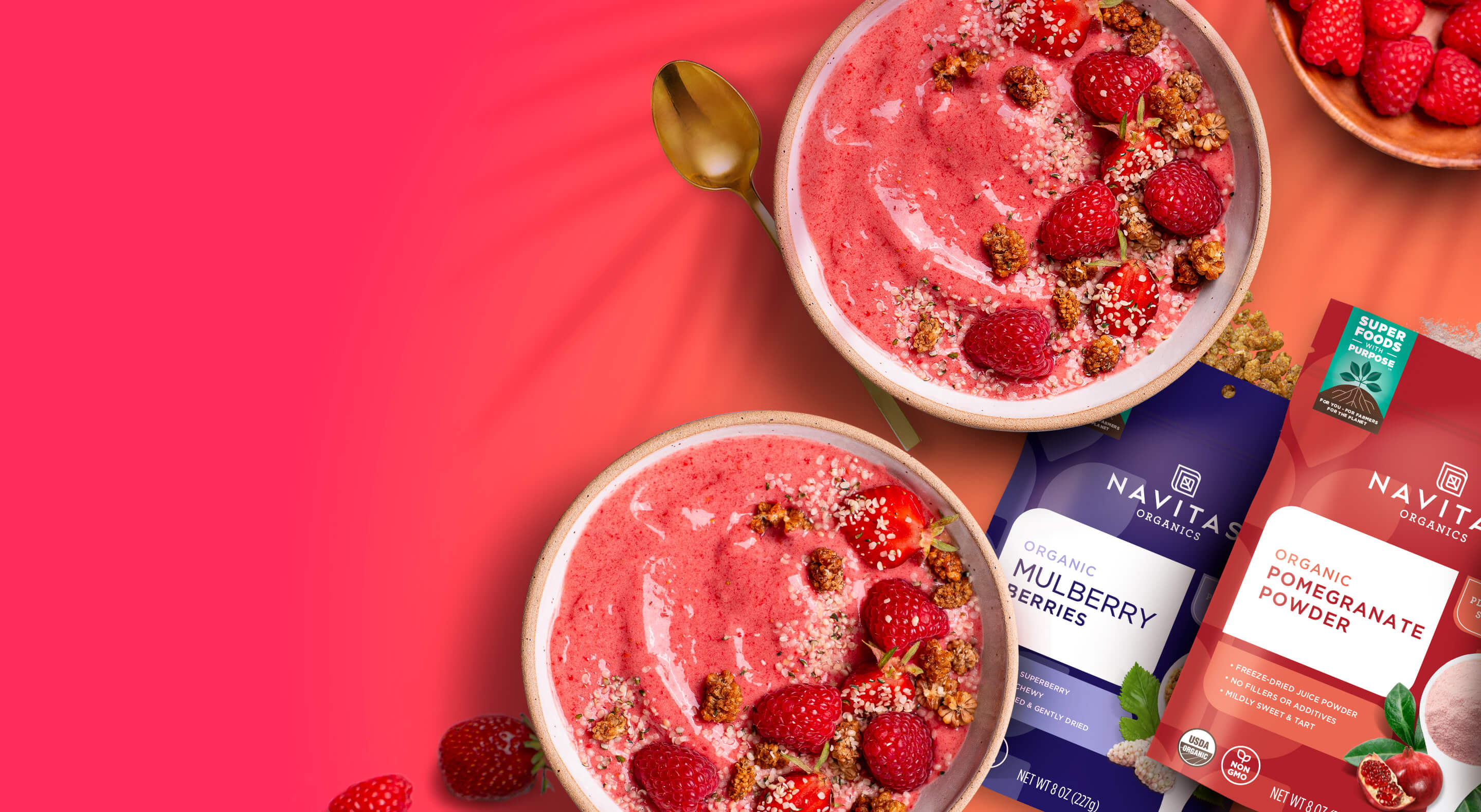 Promotional image of Navitas Organics products, featuring bowls of pink smoothies topped with raspberries and a sprinkle of mulberry, with product packets of Organic Pomegranate Powder and Organic Mulberry Berries displayed.