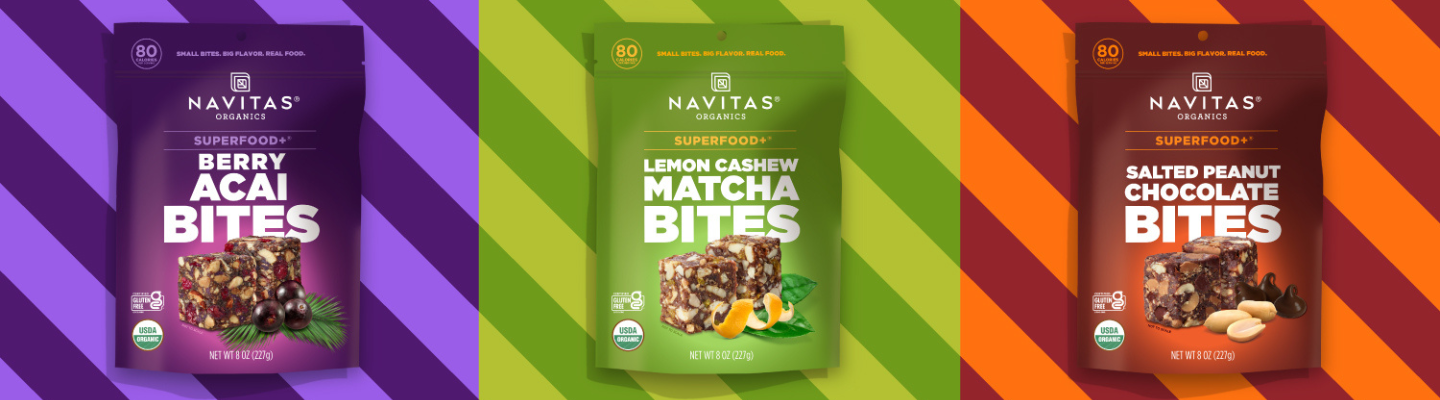 A row of Navitas Organics Superfood+ BITES featuring Berry Acai, Lemon Cashew Matcha and Salted Peanut Chocolate BITES against different colored striped backgrounds.